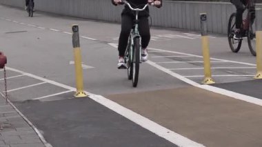 Gece ışıklarının parlamaya başladığı kalabalık bir mahallede hareketli caddelerde bisiklet sürmek