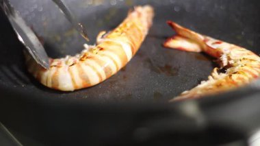 Lezzetli bir deniz mahsulü lezzeti için sıcak tavada cızırdayan karidesi izleyin.