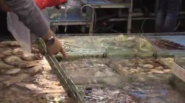 Güneşli bir öğleden sonra canlı bir pazarda taze deniz ürünleri pişirmek.