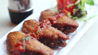 Lezzetli soslu çıtır tavuk kanatları ve sıcacık bir yemek ortamında taze süslerin tadını çıkarıyorum.