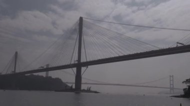 Sabahın erken saatlerinde bulutlu bir gökyüzünün altındaki bir köprünün görkemli manzarasını keşfediyorum.