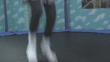 Güneşli bir öğleden sonra renkli bir bahçede trambolinde zıplayan bir çocuğun neşeli anları.