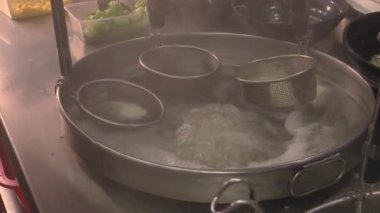 Geleneksel yemekler özen ve tutkuyla hazırlanırken, kaynayan tatlar hareketli bir mutfakta canlanıyor.