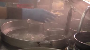 Sıcak kabarcıklar yükselirken şefler akşamın erken saatlerinde kalabalık bir mutfakta geleneksel hamur tatlısı hazırlıyorlar.