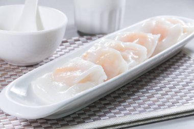 Uzun, beyaz bir tabak. Buharda pişmiş pirinç rulosu. Karidesle doldurulmuş..