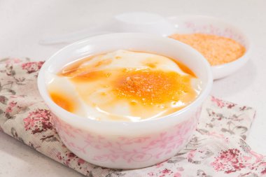 Altın şurup ve şeker tozuyla kaplanmış ipeksi fasulye kaymağı dolu çiçek desenli bir kase..