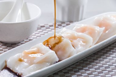 Üzerine karides ve soya sosu dökülen uzun, buğulanmış pirinç ruloları..