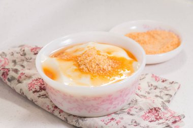 Altın şurup ve şeker tozuyla kaplı pürüzsüz fasulye kaymağı dolu çiçek desenli bir kase..