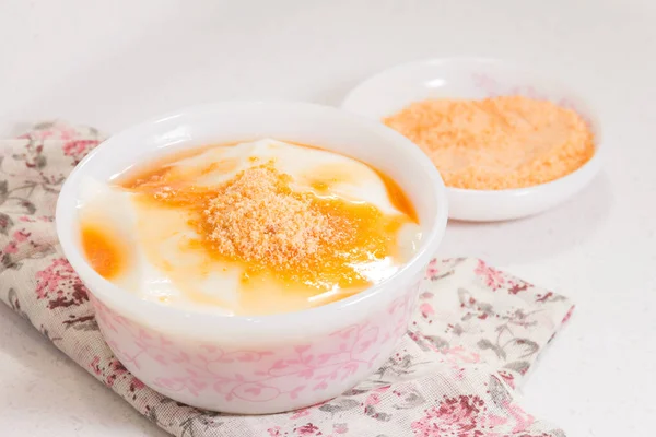 Altın şurup ve şeker tozuyla kaplı bir kase pürüzsüz soya peyniri. Çiçek bezine konmuş..