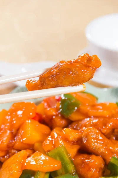 Çan biberi ve ananas parçalarıyla kızartılmış bir tabak tatlı ve ekşi domuz eti..