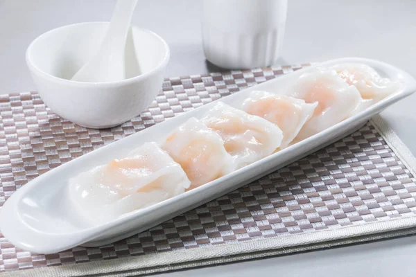 Uzun, beyaz bir tabak. Buharda pişmiş pirinç rulosu. Karidesle doldurulmuş..