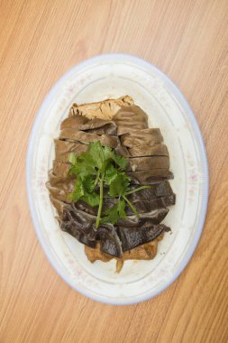 Oval bir tabak, özenle hazırlanmış tofu dilimleri ve maydanozla süslenmiş..