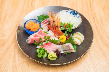 Karides, ton balığı ve garnitürlü deniz kestanesi içeren büyük yuvarlak bir tabak..