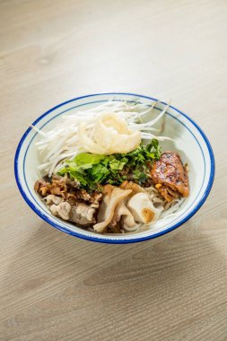 Bir kase Vietnam eriştesi çorbası, taze otlar, fasulye filizi ve çeşitli et dilimleri..