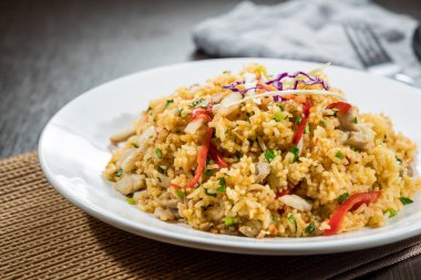 Beyaz bir tabakta servis edilen, sebze ve etle karıştırılmış yakın plan kızarmış pirinç..