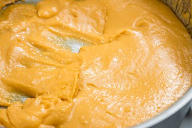 Metal bir tavada kremalı fıstık sosu, pürüzsüz doku ve altın rengi..