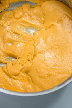 Metal bir tavada kremalı fıstık sosu, pürüzsüz doku ve altın rengi..