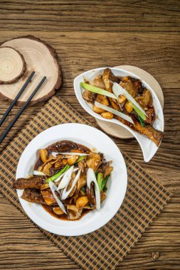 İki tabak soya sosunda pişirilmiş balık fileto sarımsak ve ahşap masada servis edilen yeşil soğanlı..