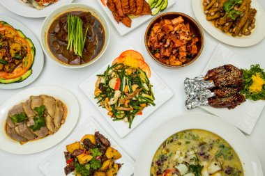 Etler, deniz ürünleri, sebzeler ve beyaz bir masaya dizilmiş çorba da dahil olmak üzere çeşitli Çin yemekleri..