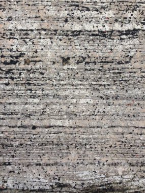 Koyu lekeleri ve yatay çizgileri olan sert beton bir duvarın yakın görüntüsü doku oluşturur.
