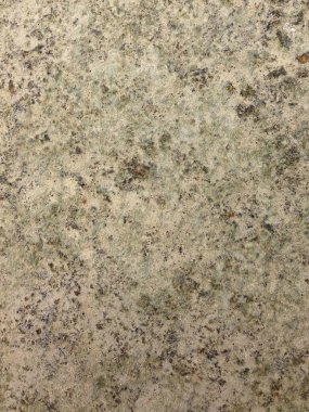 Düz yamaları ve pürüzlü yüzeyi olan yıpranmış bir duvarın yakın çekimi.