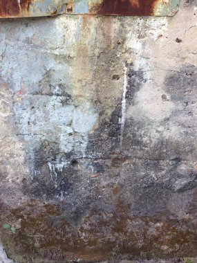 Düz yamaları ve pürüzlü yüzeyi olan yıpranmış bir duvarın yakın çekimi.
