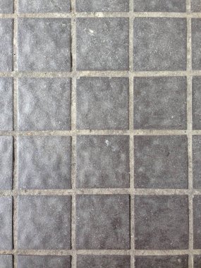 Bir zemin yüzeyinde düzgün bir ızgara desen içinde düzenlenmiş gri kare karoların yakın çekimi.