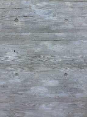 Yatay ahşap dokusunu ve dairesel girintileri gösteren beton duvarın yakın çekimi