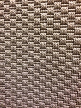 Kare dikişli deseni ve desenli yüzeyi gösteren bej dokuma kumaşın yakın çekimi