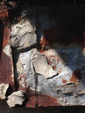 Paslanmış metal yüzeyin yakın çekimi, soyulmuş boya ve aşınma izlerini gösteriyor.