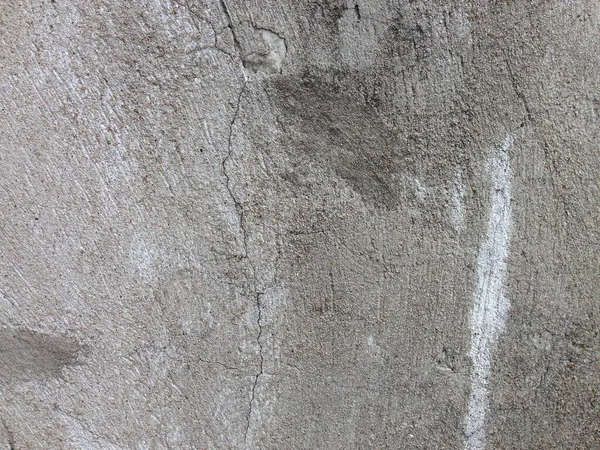 Görünür çatlaklar ve pürüzlü dokuyu gösteren yıpranmış beton duvarın yakın çekimi