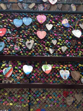 Renkli asma kilitlerle kaplı dekoratif bir duvar ve kablolarda asılı tahta kalpler..