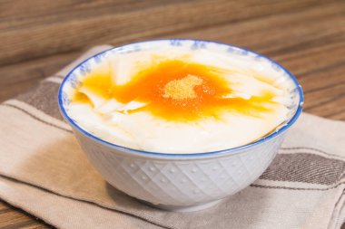 Altın şurup ve şeker tozuyla kaplı pürüzsüz fasulye kaymağı dolu çiçek desenli bir kase..