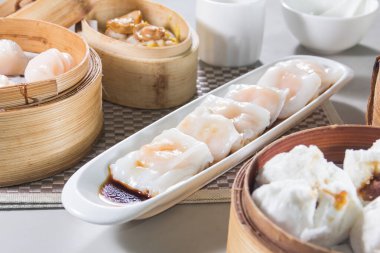 Uzun beyaz buharda pişmiş pirinç ruloları karides dolu, soya sosuyla ıslatılmış, bambu budan yapılmış Çin buharlı buharlı vapurlarla çevrili..