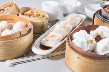 Bambu tencerelerinde servis edilen karides köfteleri, pirinç ruloları ve domuz ızgara çörekleri de dahil olmak üzere çeşitli Dim Sum yemekleri..
