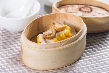 Bir bambu buharlı buhar tenceresi, üzerinde küçük bir deniz kulağı parçasıyla, bir hasırın üzerine yerleştirilmiş..