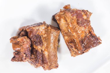 İki parça ağır ateşte pişmiş et, beyaz bir tabağa konmuş, sosu ve yumuşak dokusunu gösteriyor..