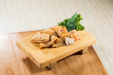 Ahşap tahta, terbiye edilmiş mürekkep balığı dilimleri yeşil garnitürle düzgünce dizilmiş..