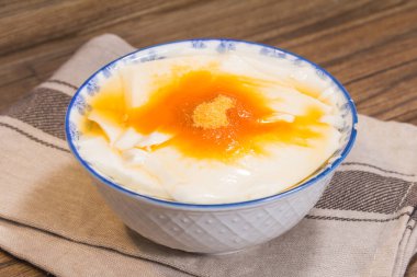 Altın şurup ve şeker tozuyla kaplı pürüzsüz fasulye kaymağı dolu çiçek desenli bir kase..