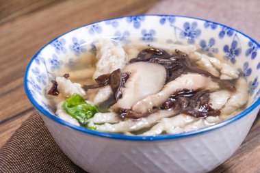Çiçek desenli çorba, tavuk dilimleri, siyah mantar ve mantarlarla dolu bir kase..