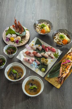 Bütün bir balık başı ve kuyruğu sağlam bir şekilde hazırlanırken vücut tek parça halinde kesilip beyaz bir tabakta yelpazeleniyor. Gümüş deri ve kırmızı karıncalanmış et, ahşap arka planda göze çarpar.