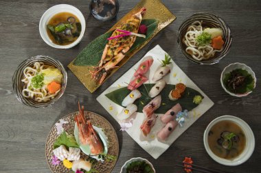 Üzerinde çeşitli nigiri 'ler, ızgara karides, bir kase udon, temiz çorba ve küçük kenarlardan oluşan bir set. Yapraklar ve seramiklere mevsimsel dokunuşlar eklenerek, rafine ve uyumlu bir Japon sunumu eklenir..