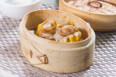 Bir bambu buharlı sepet. İki shumai hamur köftesi. Üstüne de bütün deniz kulağı parçaları örülmüş..