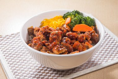 Baharatlı tavuk parçaları, dilimlenmiş yumurta ve sebzeli bir kase haşlanmış pilav.