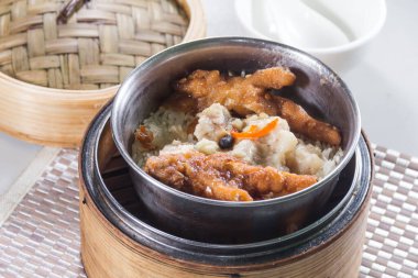 Bambu buharlı buharda pişirilmiş tavuk ayaklarıyla pişirilmiş metal bir kase pirinç.