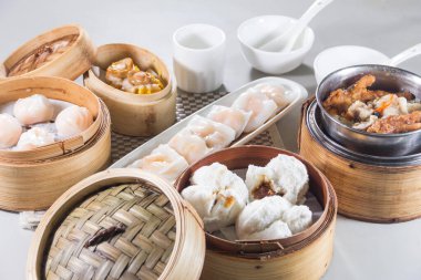 Karides köftesi, çörek ve domuz pirzolası içeren bambu buharlı bir masa seti. Beyaz kâseler ve kaşıklarla servis ediliyor..