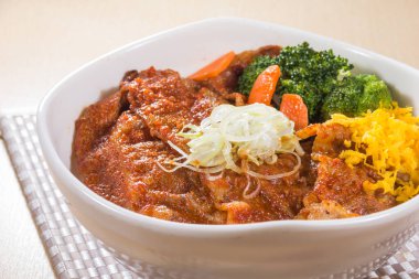 Kırmızı soslu dilimlenmiş domuz eti, dilimlenmiş yumurta, soğan ve brokoli ve havuçla kaplı doyurucu bir pirinç kasesi. Yakın görünüm, iştah açıcı ana resim için dokuyu ve rengi vurgular.