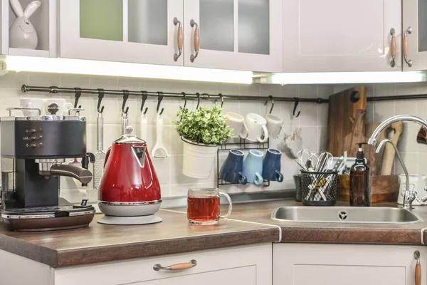 Red electric kettle in retro stile with coffee machine in kitchen interior