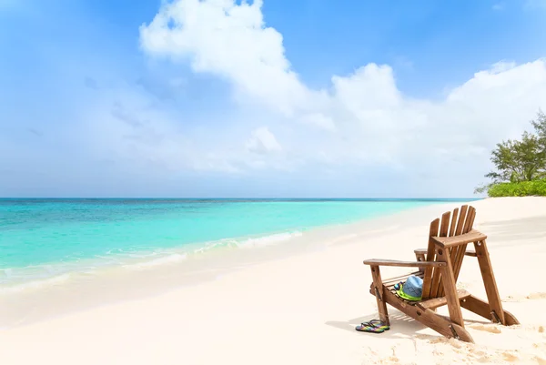 Silla de playa de madera con sombrero y zapatillas en la playa tropical, summ — Foto de Stock