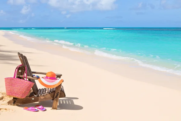 Silla con bolsa, sombrero, chanclas y gafas de sol en la playa soleada, t — Foto de Stock